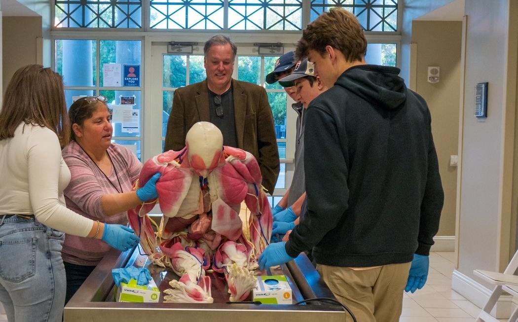 Alumni Gathered Around a Table with a Synthetic Cadaver.