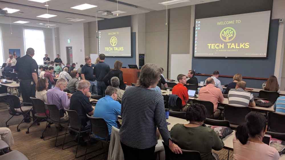 A large group of people seated at tables during tech talks