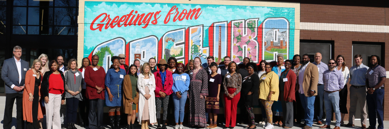 Image of class participants in Opelika Entrepreneurship Workshop standing in front of Greetings from Opelika mural