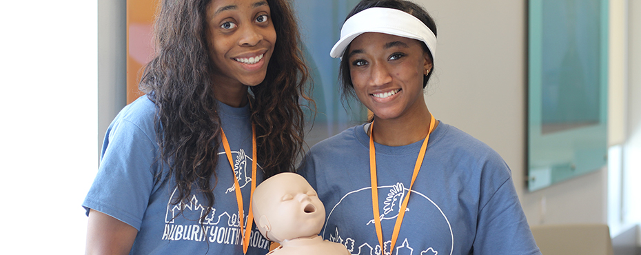 students posing with infant CPR doll