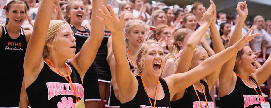 A group of cheerleaders cheer for their squad members during competition while at National Cheerleaders Association Camp.