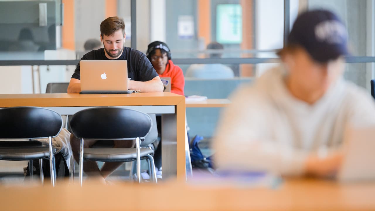 student sitting at a table with a laptop