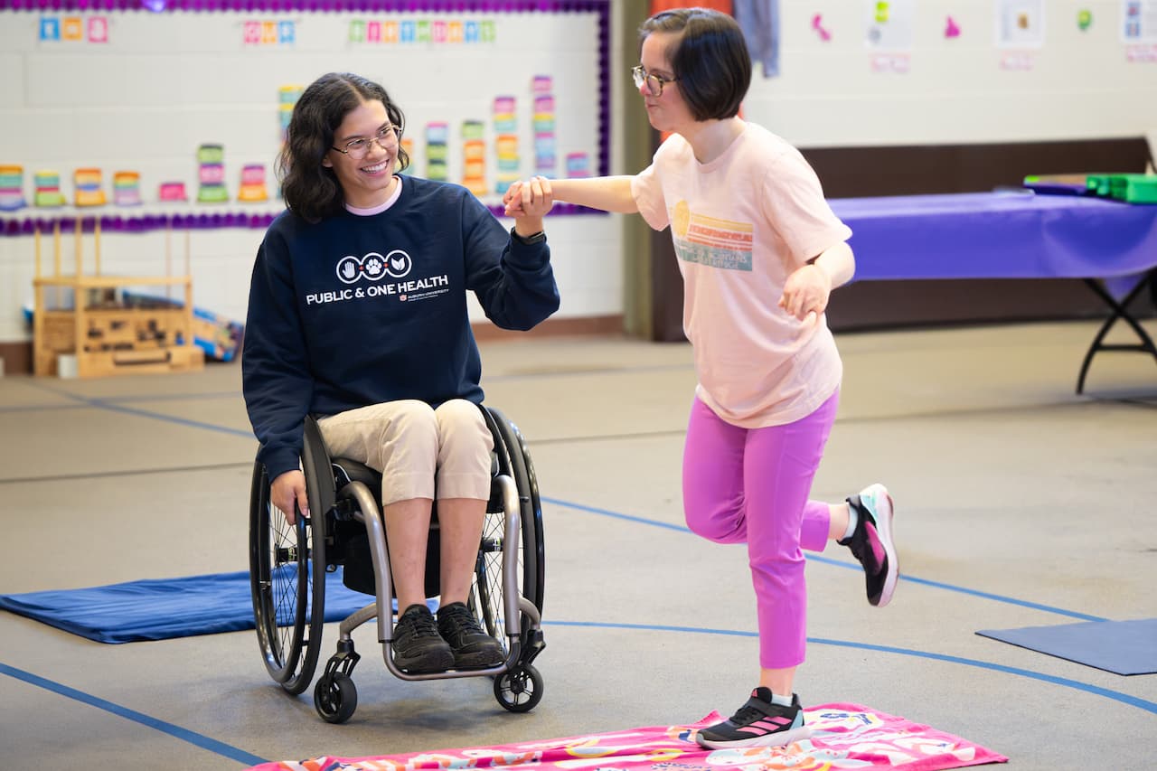 girl in wheelchair help another girl play hopscotch