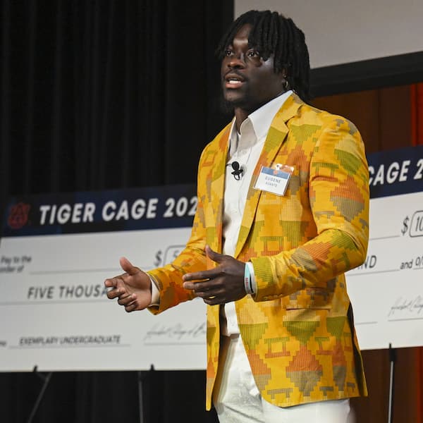 man standing on stage in front of large checks