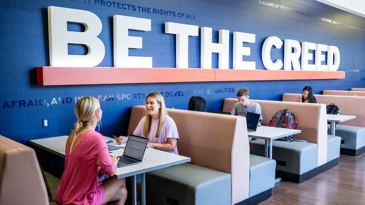 two students sitting at a table under the Creed