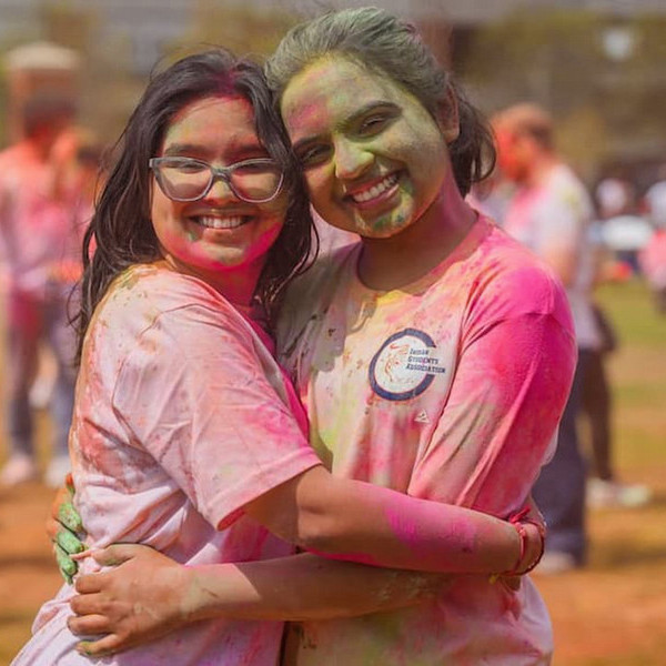 two students hugging and smiling covered in paint