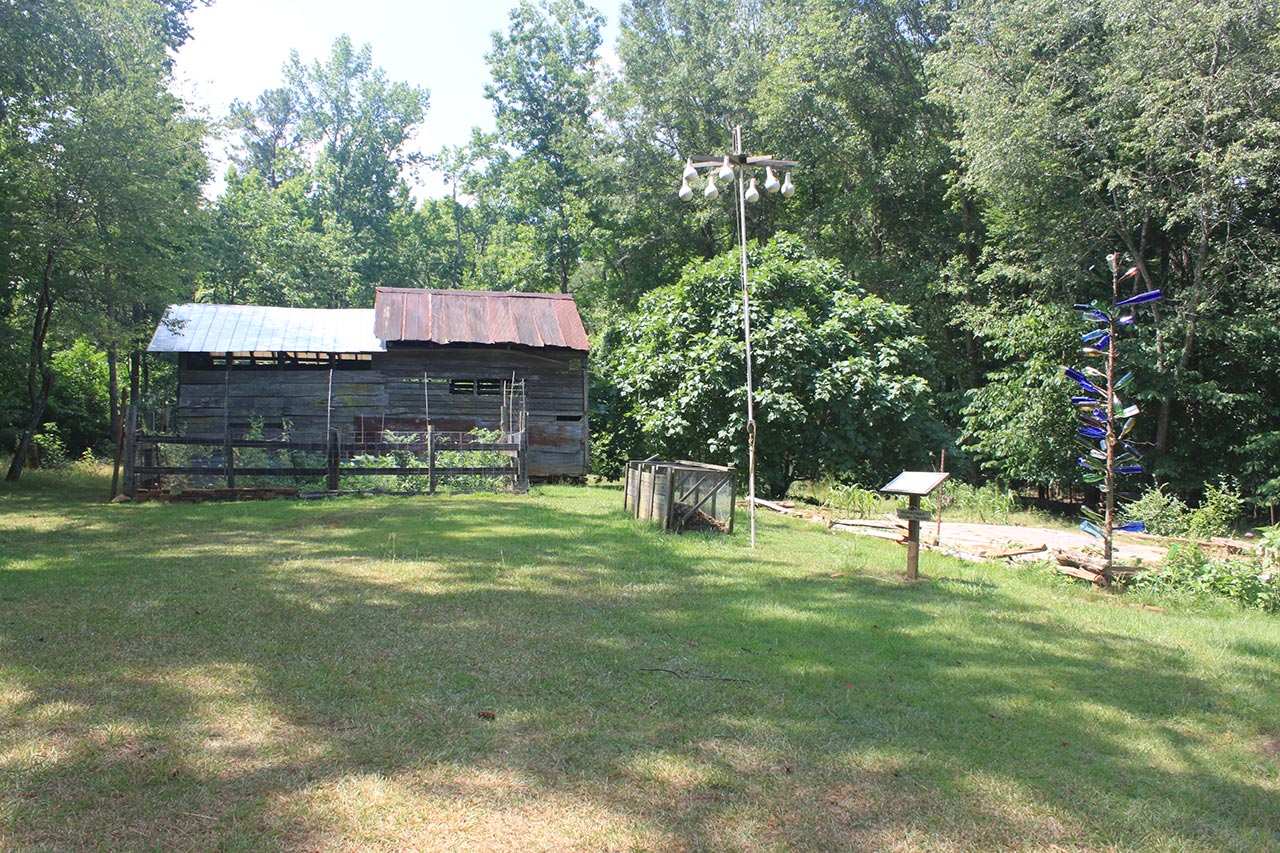 An old barn is pictured in a grassy opening