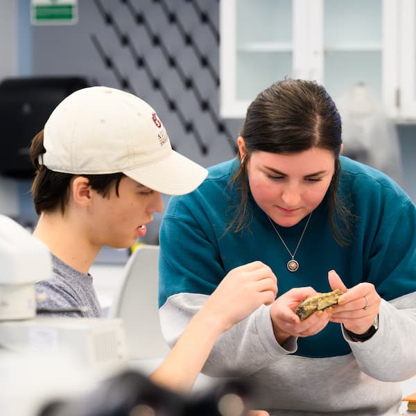 student and faculty member looking at a rock together