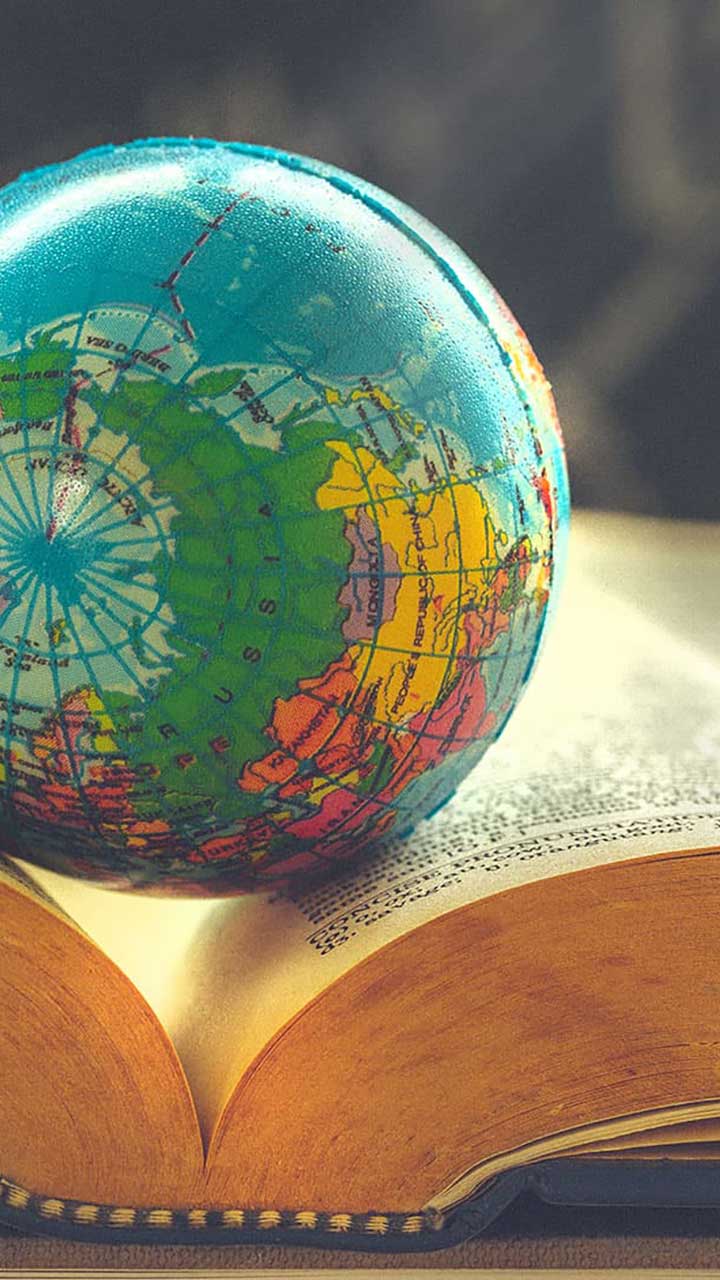 Graphic of a globe resting in the crease of an open book.