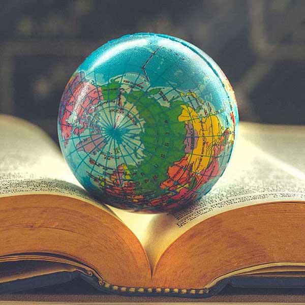 Graphic of a globe resting in the crease of an open book.