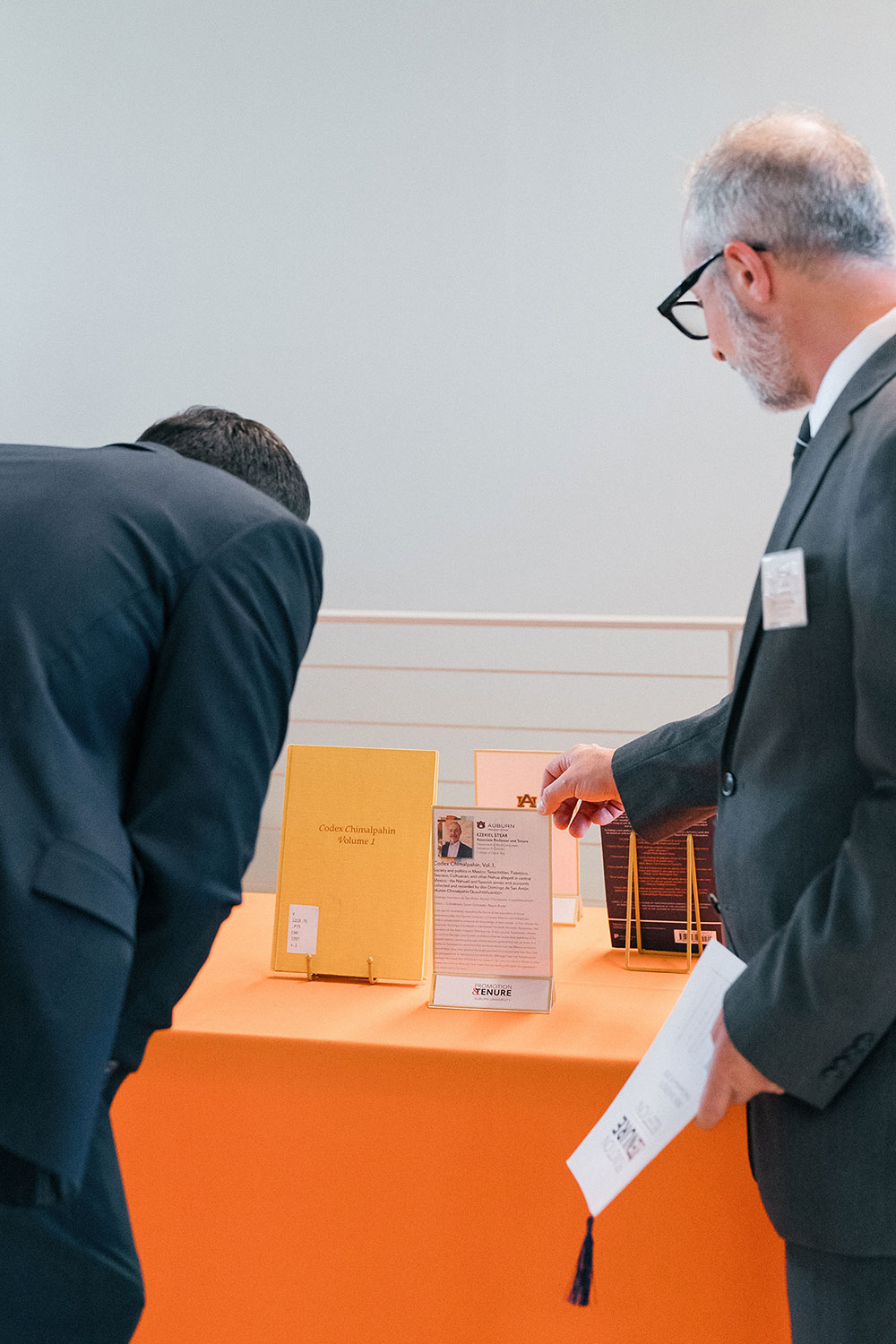 Promotion and Tenure 2025 attendees reading a showcased book