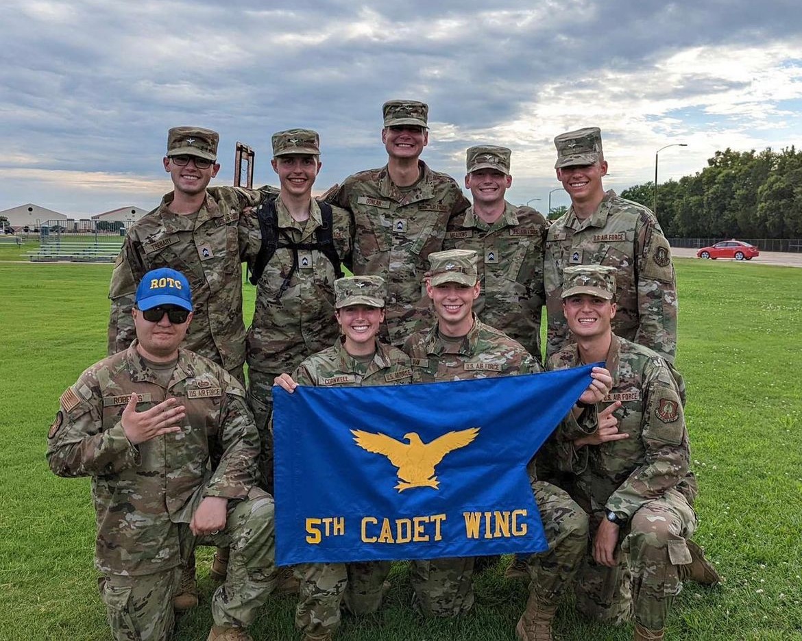 Group of cadets holding 5th cadet wing pennant