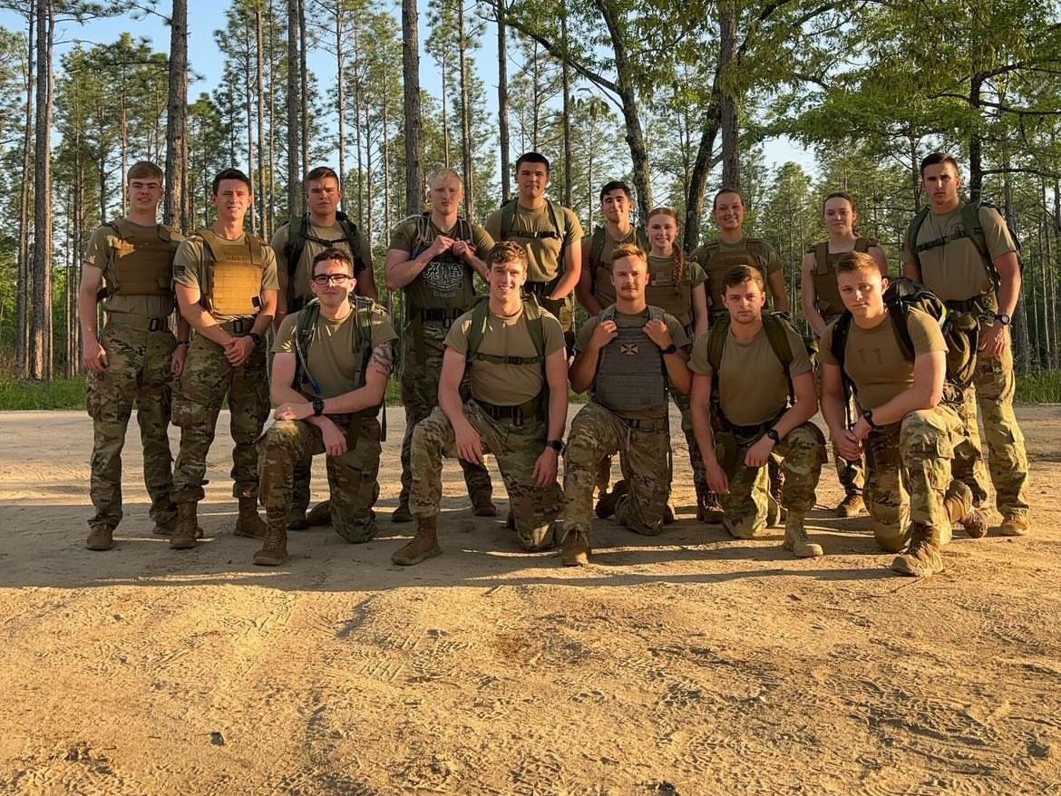 Image of cadets wearing weight vests posing before a ruck.