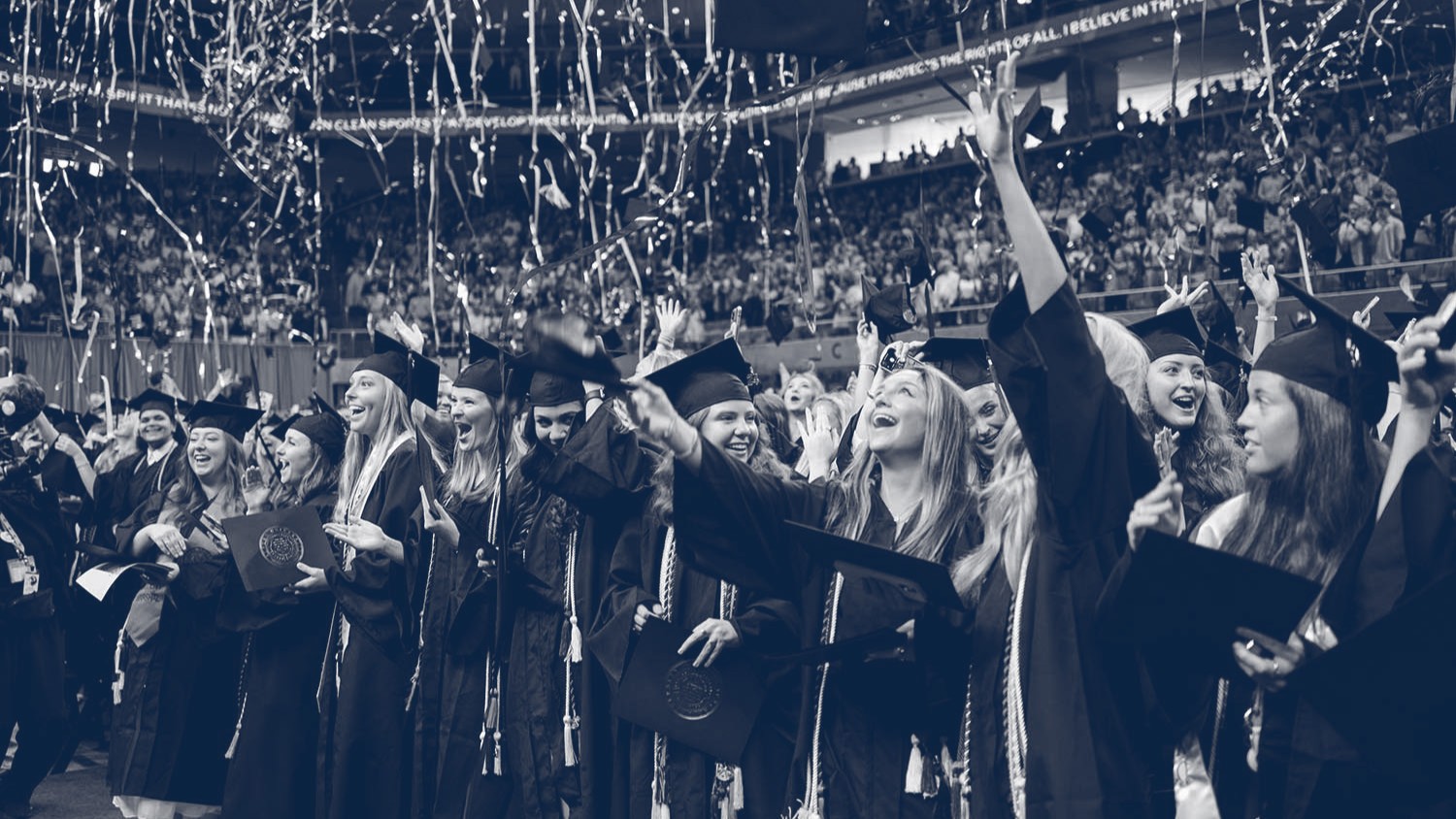 graduates celebrating while streamers fall at graduation