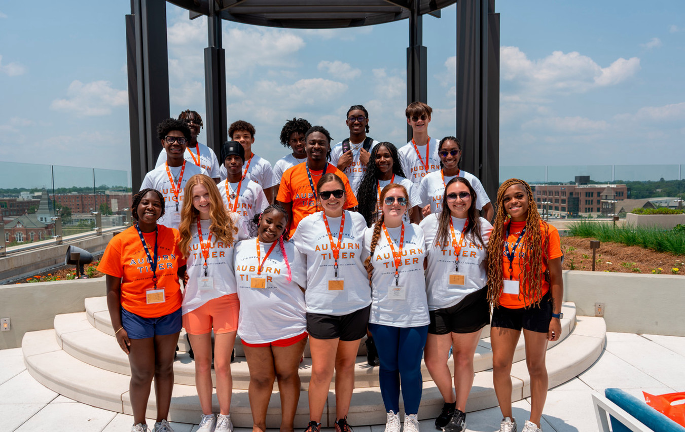 A summer program participant holding science equipment performing an experiment in an Auburn classroom.