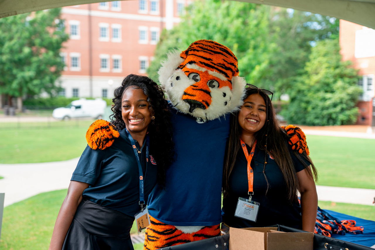 Two students smiling with Aubie at Tiger Takeoff check-in.