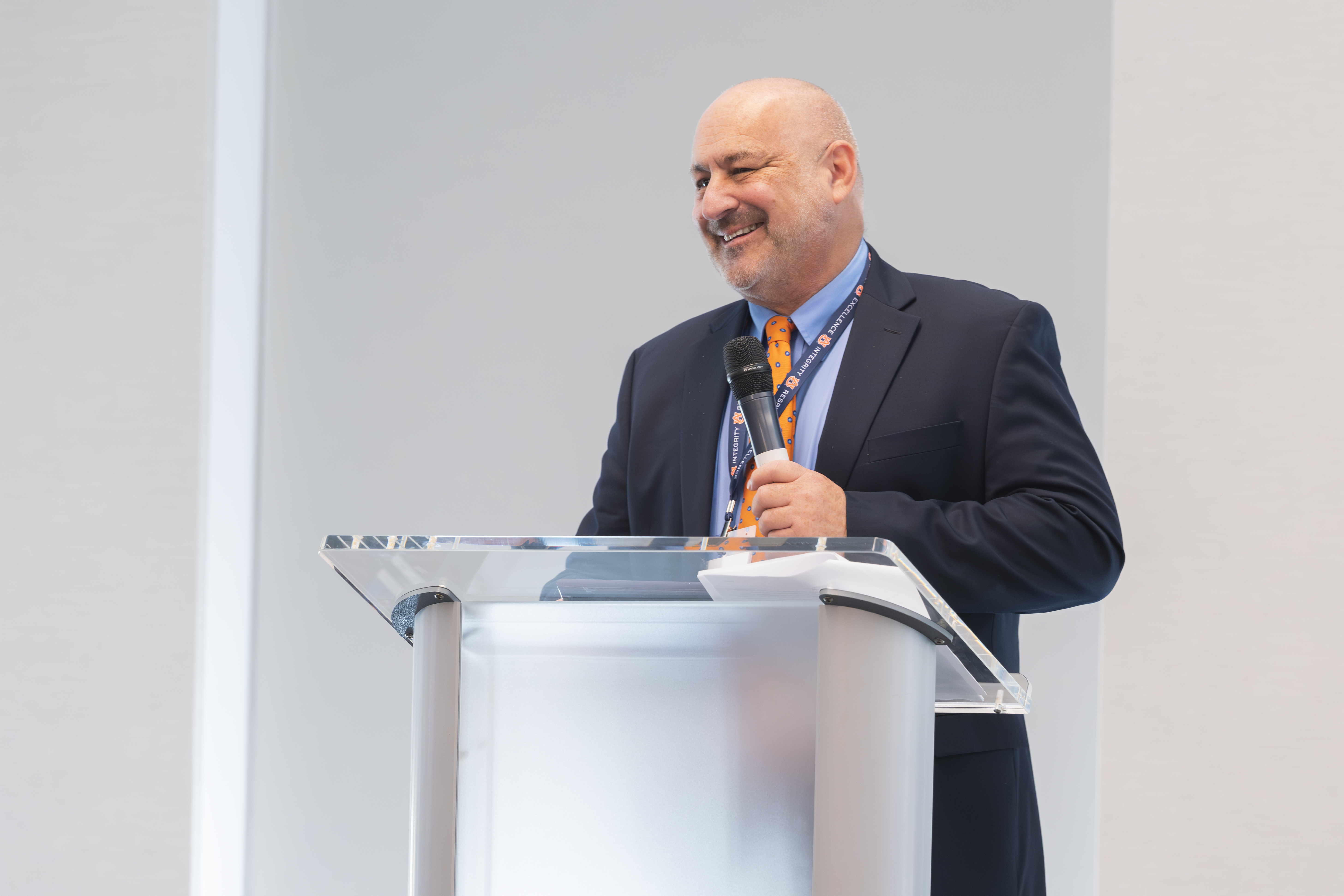 2025 Compliance Champion Award Winner, Robert G., standing at podium smiling and speaking to audience on mic