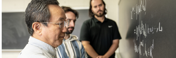 a group of mathematicians writing figures on a chalkboard