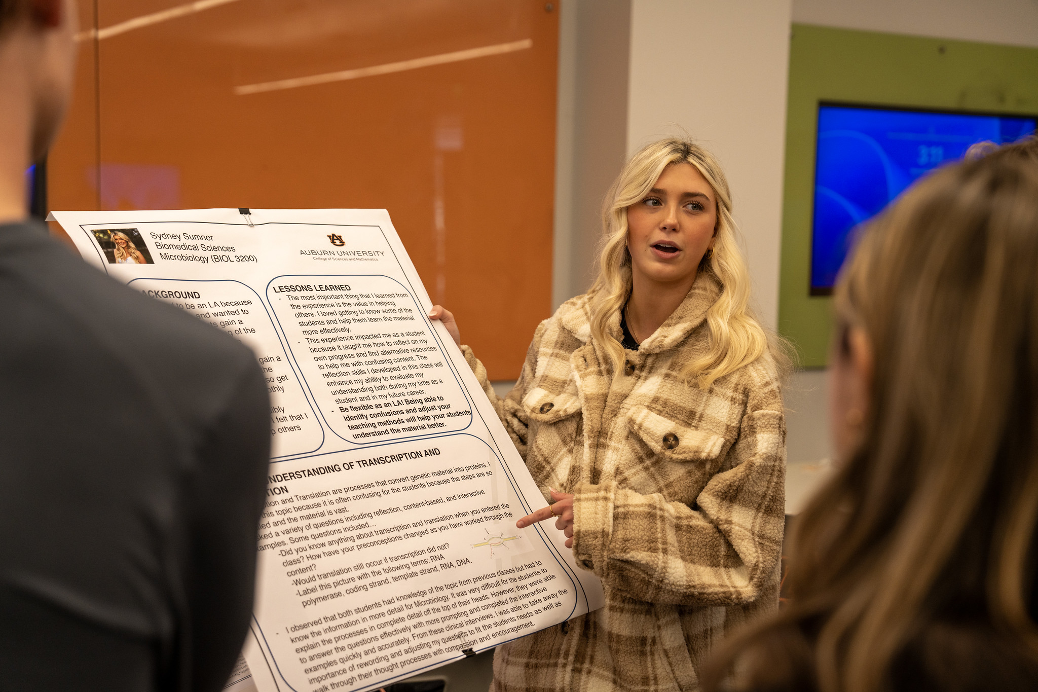 a student presenter stands alongside her poster 
