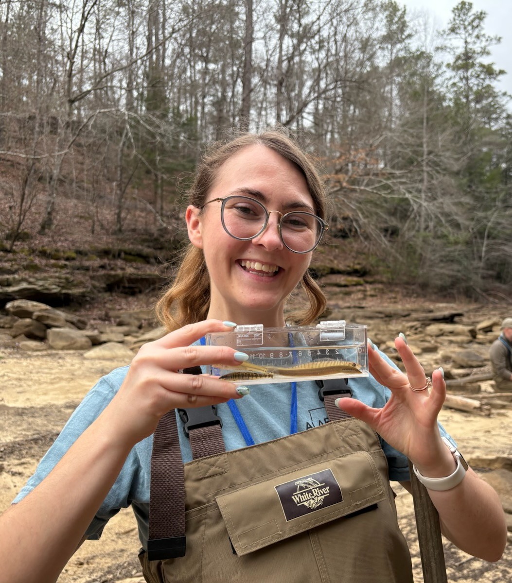Jordan Bralley holding a water sample and smiling
