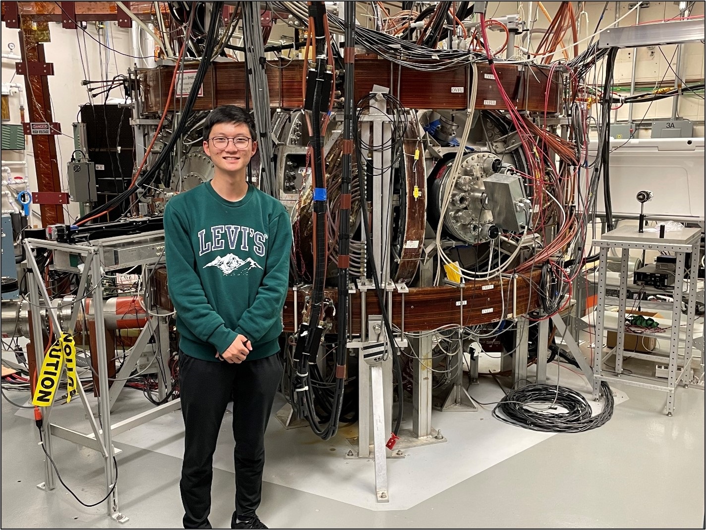 Noah Kim standing in front of the Compact Toroidal Hybrid plasma device at Auburn.