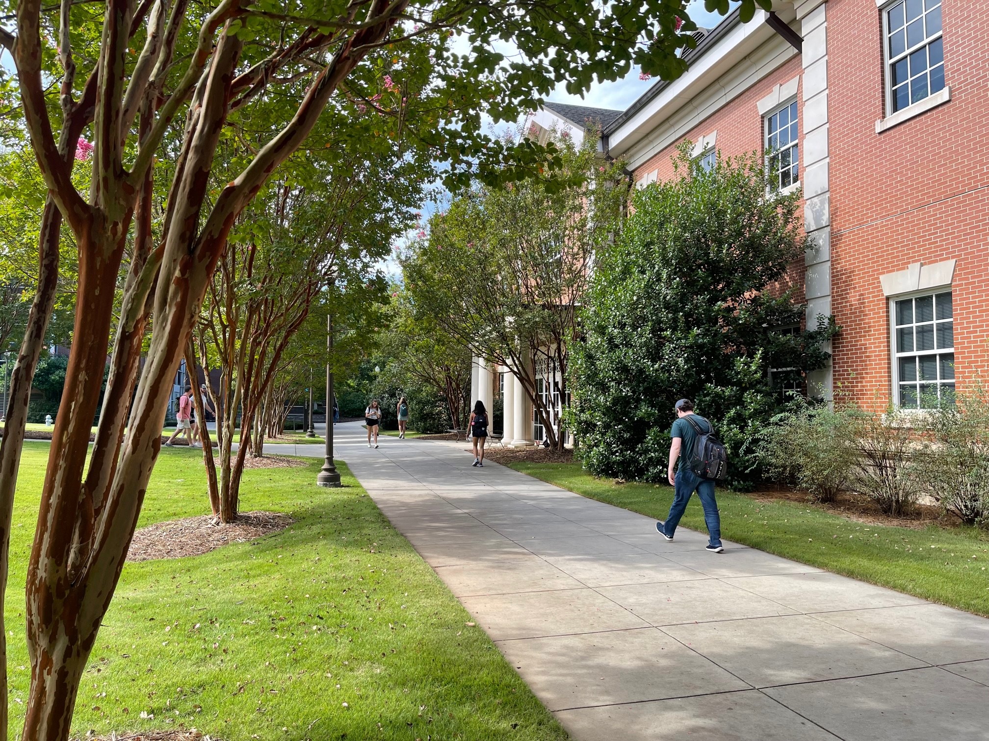 Student walking down sidewalk by SCC building
