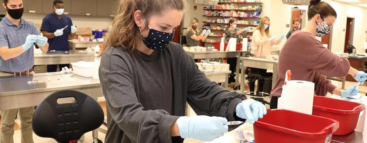 A masked student works in a lab.