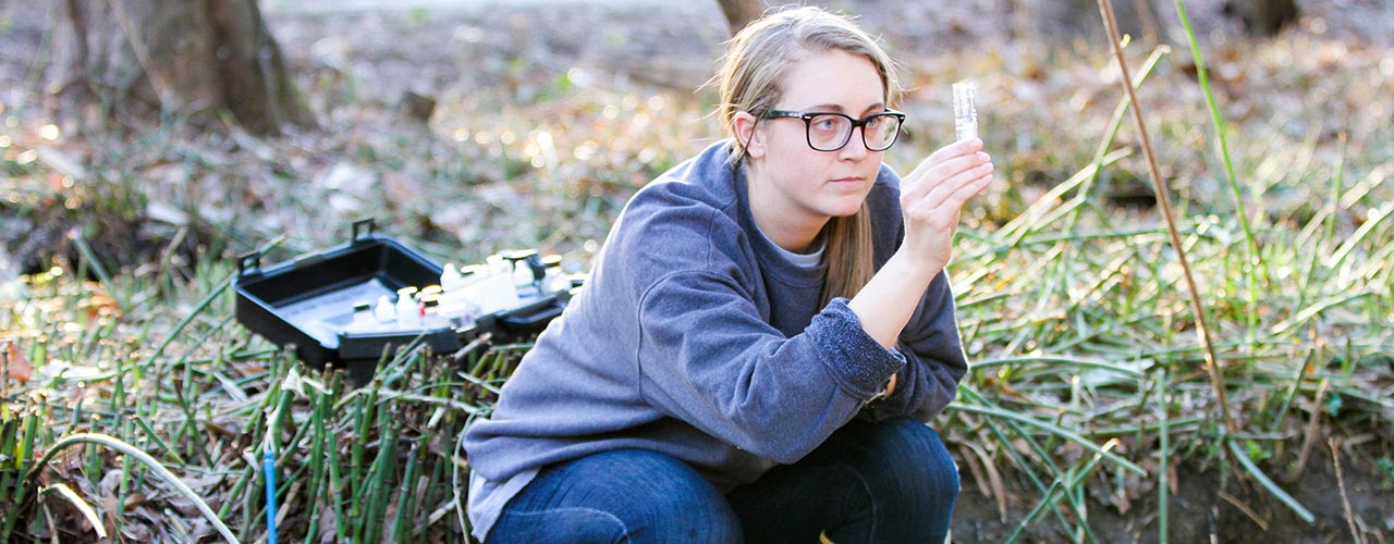 A student examines a vial of water.