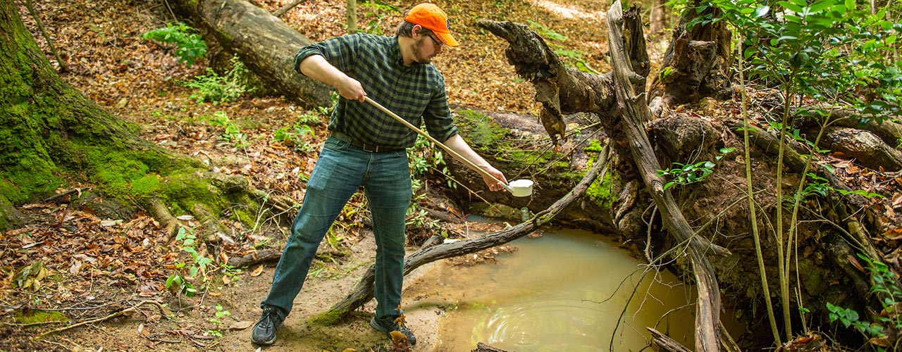 A collects water samples outside.
