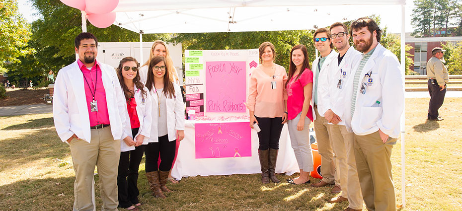 Group photo of AU pharmacy students posing with display at All in All Pink event