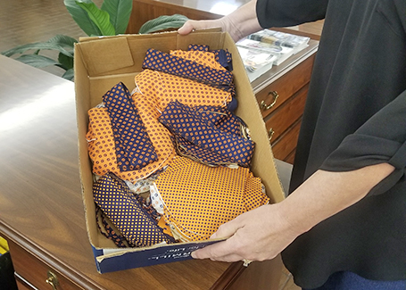 Hands holding box of cut out fabric for face masks