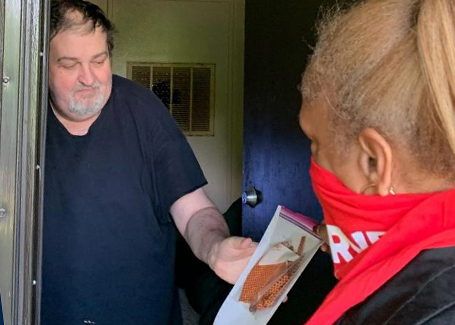 Man, opening front door, reaches for donated mask from Church of Highlands outreach volunteer