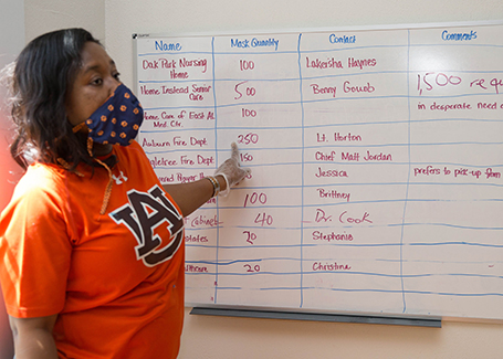 Elizabeth Essamuah-Quansah points at white board with locations listed that have requested masks.