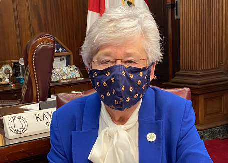 Governor Kay Ivey sits in her office wearing orange and blue AU mask.