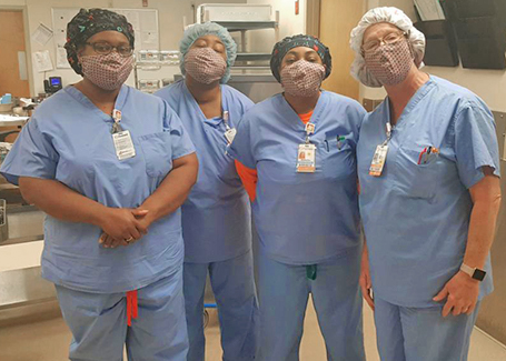 Four people in scrubs wear orange and blue face masks.