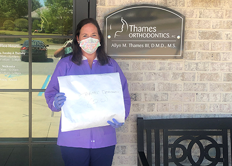 Woman holding bag of donated masks stands in front of orthodontics office.