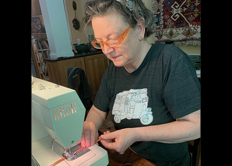Scott sits at her sewing machine working on making face masks.