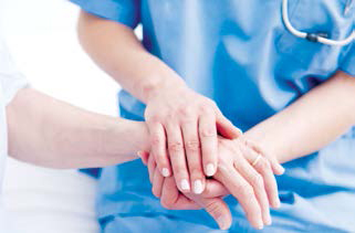 Doctor wearing scrubs holding patient's hand