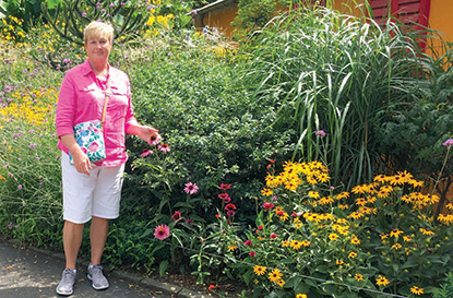 Woman wearing pink stands in front of colorful flower garden