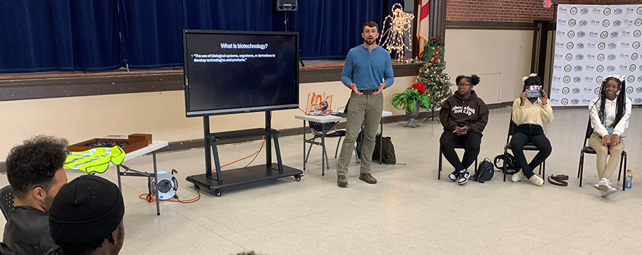 A male guest speaker presents to a group of students in a school auditorium