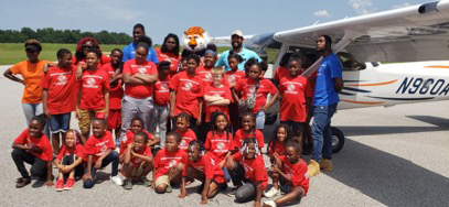 Boys and Girls club members pose in front of airplane at Auburn Airport