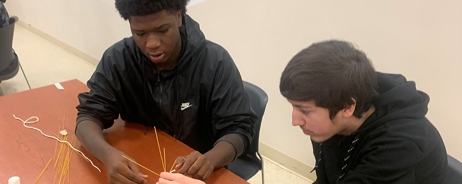 2 male students collaborate to build a project for a classroom activity