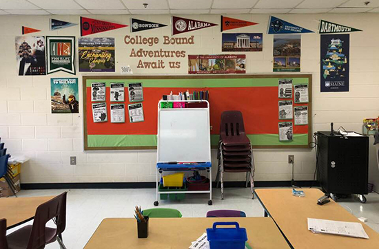 Classroom with bulletin board and college penants around it.