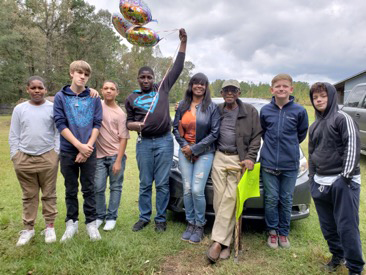 Lee County Youth Development Center's landscape class poses in front of car with balloons.