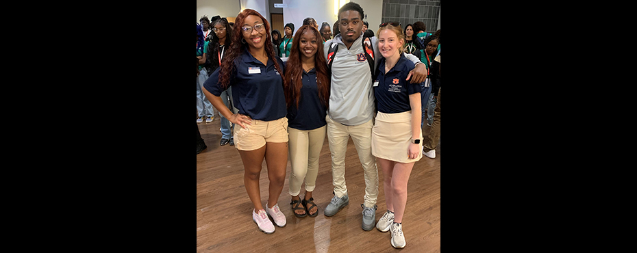 3 female and 1 male student stand for a picture in a lobby area