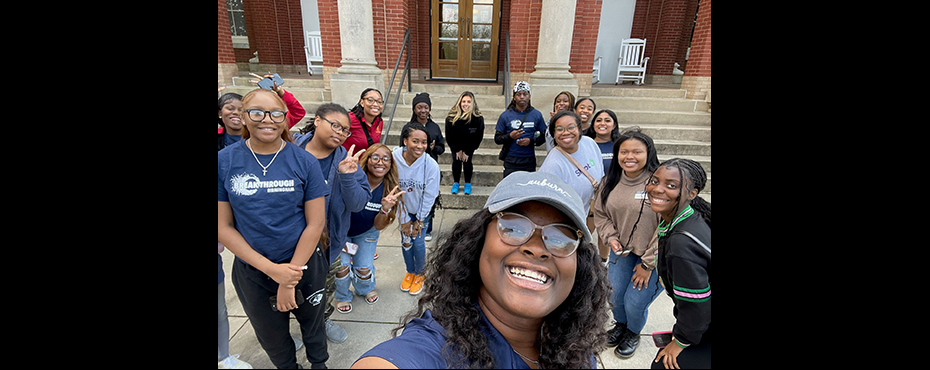 A large group of male and female students take a picture outside while on a college tour.