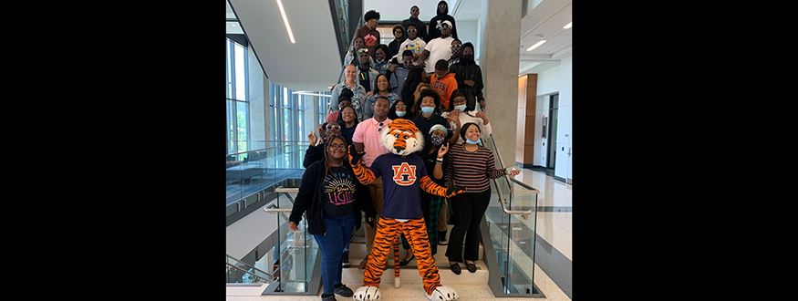 A group of male and female students pictured with Aubie on a stairwell