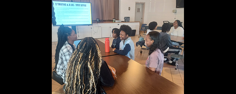 A small group of male and female students participate in a ice breaker interactive session in an event center auditorium