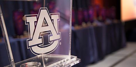Interlocking AU logo on clear podium with blurred background