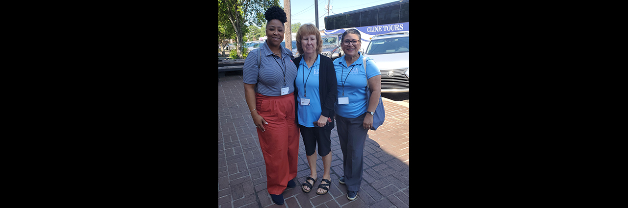 Three female event attendees standing on a sidewalk